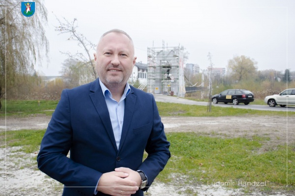 Prezydent Miasta Nowego Sącza na tle powstającego muraluna filaru kładki wiszącej nad Kamienicą