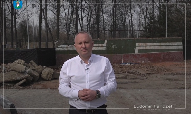 Prezydent Ludomir Handzel na tle kortów tenisowych.